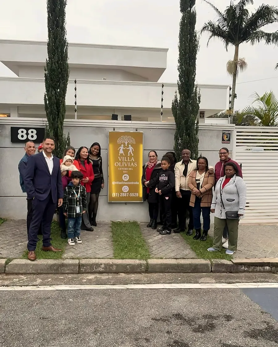 Convidados e família reunidos diante da placa do Villa Olívias no dia da inauguração