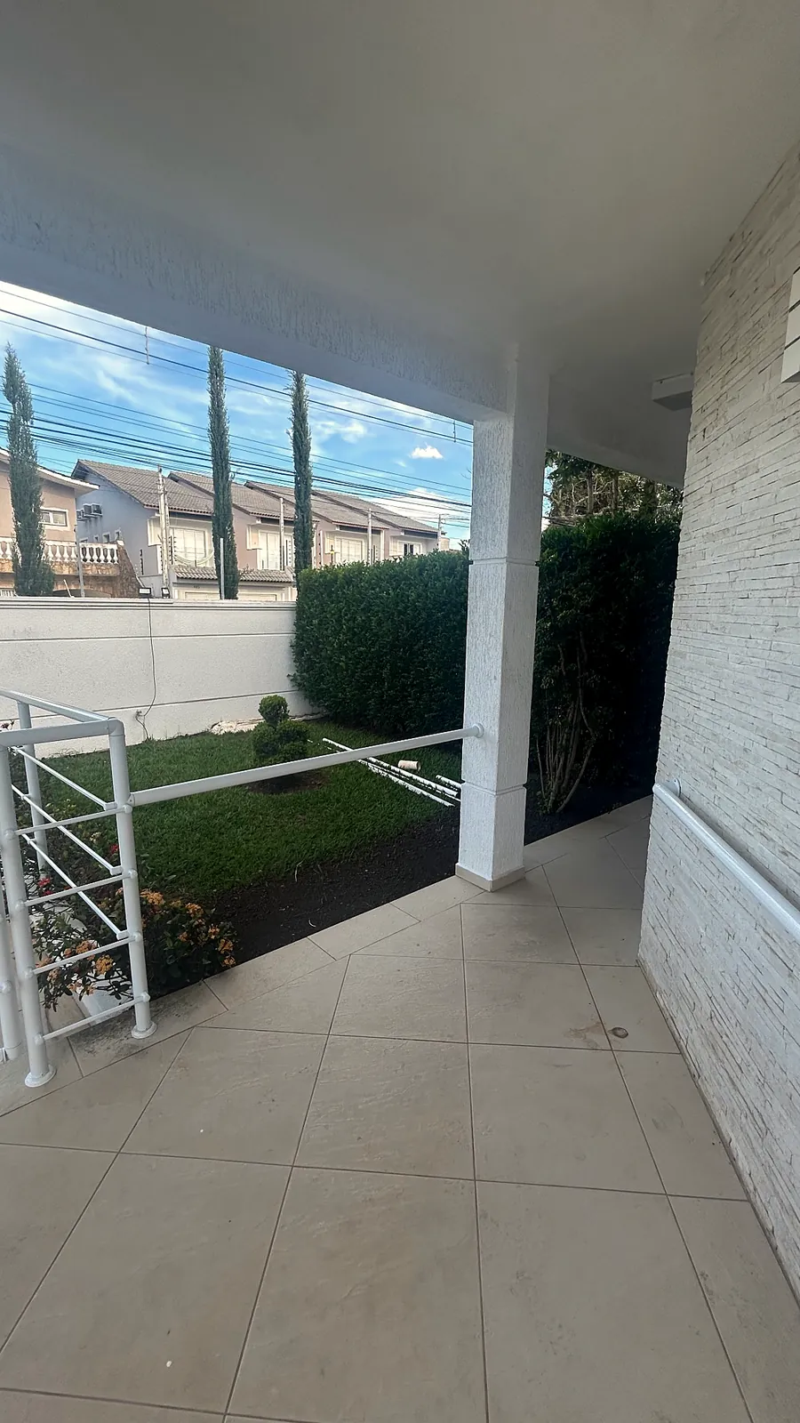 Varanda coberta com vista para o jardim e a cerca viva